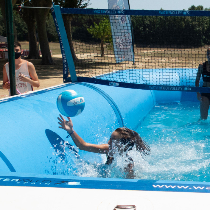 Jugadora de watervoley se tira a por un balón en una piscina deportiva profesional de water sport pools®